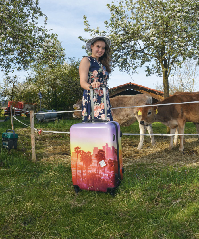 Frau steh mit Koffer vor Kälber